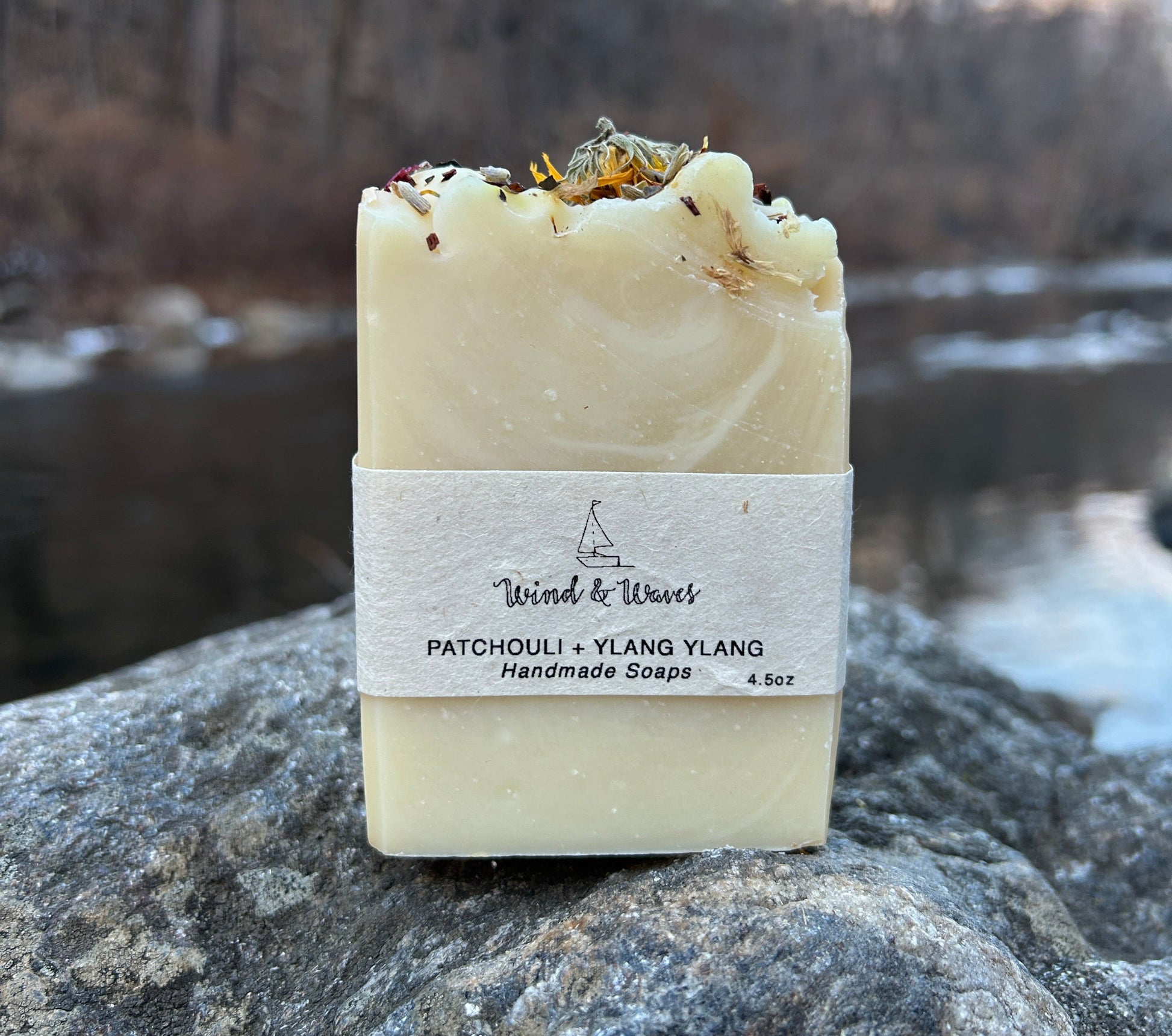 Handmade patchouli and ylang ylang soap bar infused with mixed dried flowers and scented with patchouli, ylang ylang, and lemon essential oils. Made with organic coconut oil, olive oil, mango seed butter, and shea butter for a nourishing and aromatic cleanse. Each bar weighs approximately 3 ounces and is wrapped in eco-friendly lokta paper.