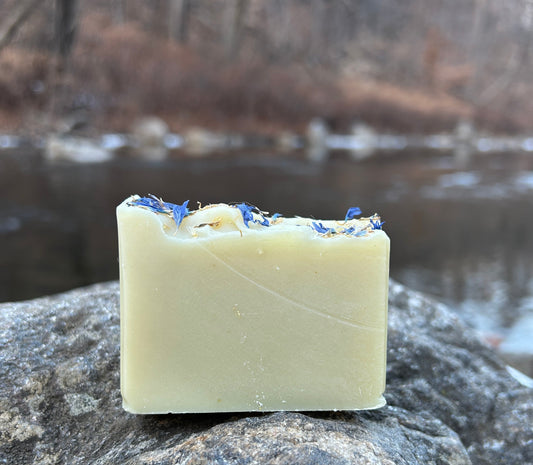 Handmade anise and lime soap bar, enriched with organic coconut oil, olive oil, shea butter, mango seed butter, and cocoa butter. Features natural colorants like spinach powder and French green clay, with cornflower petals for a decorative touch. Scented with anise, lime, and peppermint essential oils. Each bar weighs approximately 3 ounces and is wrapped in eco-friendly lokta paper.