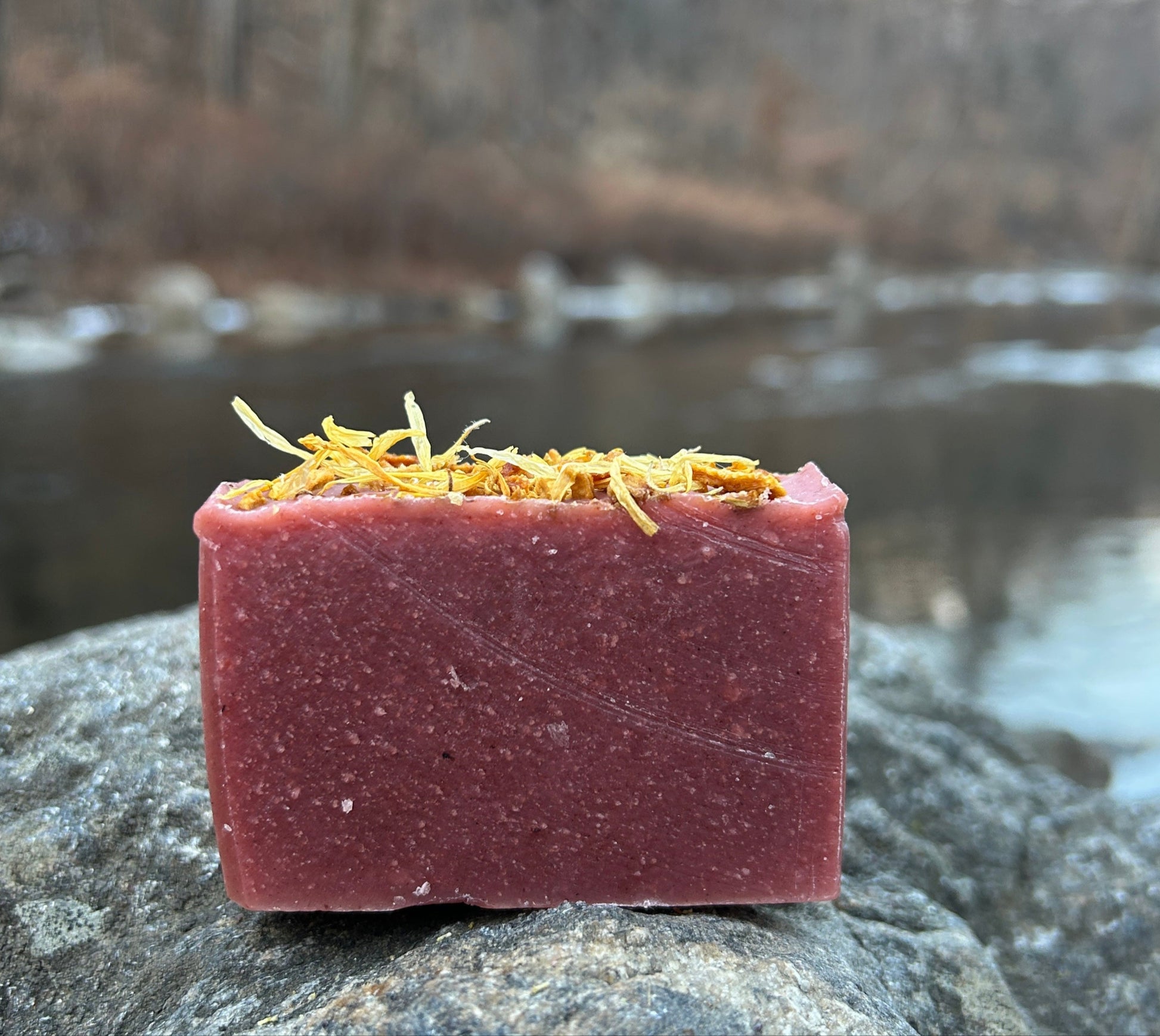 Handmade citrus spice soap bar infused with calendula flowers, dried orange peel, and cinnamon. Crafted with organic coconut oil, calendula flower-infused olive oil, shea butter, and mango seed butter for a nourishing cleanse. Naturally colored with madder root powder and scented with orange essential oil. Each bar weighs approximately 3 ounces and is wrapped in eco-friendly lokta paper.