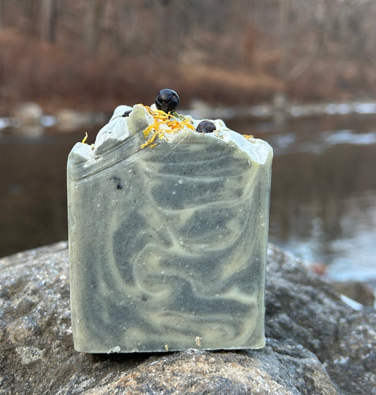 Handmade rosemary and fir soap bar infused with calendula tea, activated charcoal, and kaolin clay for a deep yet gentle cleanse. Crafted with organic coconut oil, olive oil, shea butter, and mango seed butter for nourishing care. Accented with calendula flowers and juniper berries, and scented with rosemary and fir essential oils for a fresh, woodsy aroma. Each bar weighs approximately 3 ounces and is wrapped in eco-friendly lokta paper.